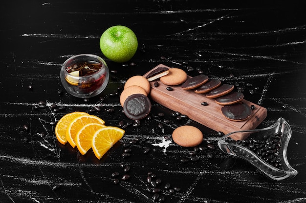 Chocolate sponge cookies on a wooden board with herbal tea.