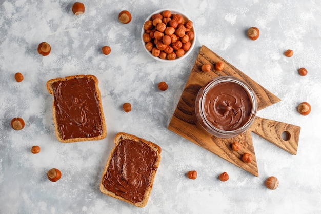 Chocolate spread or nougat cream with hazelnuts in glass jar on concrete ,  copyspace