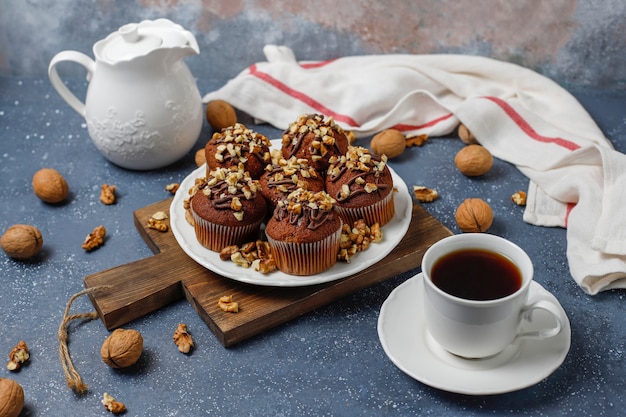 Free photo chocolate-walnut muffins with coffee cup with walnuts on dark surface