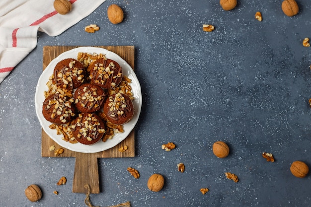 Free photo chocolate-walnut muffins with coffee cup with walnuts on dark surface