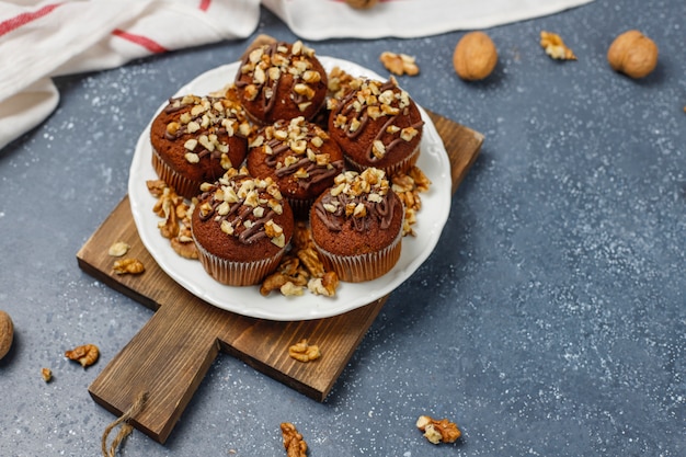 Free photo chocolate-walnut muffins with coffee cup with walnuts on dark surface