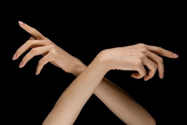 Choosing a right way. Male and female hands demonstrating a gesture of getting touch isolated on black studio background. Concept of human relations, relationship, feelings or business.