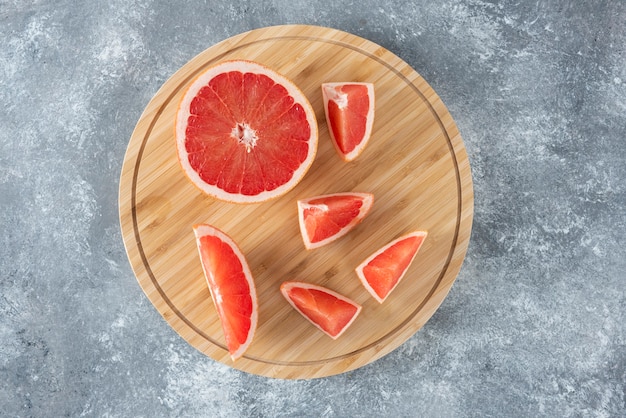 Chopped fresh sour grapefruit placed on a wooden round board . 