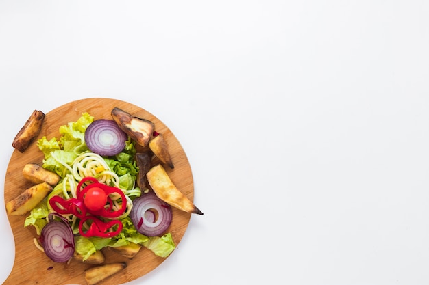 Free photo chopped vegetables and roasted potato on wooden cutting board over white background