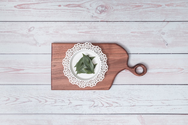 Free Photo chopping board with ornament plate and green leaves