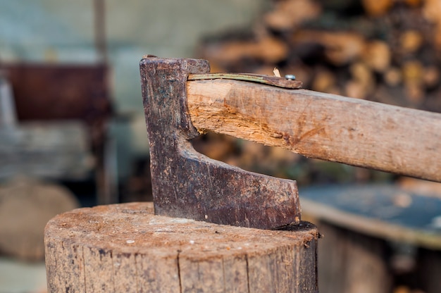 Free photo chopping wood with ax. ax stuck in a log of wood. old, worn, scratched, sharp ax standing on a wooden, cracked tree stump on a background of chopped wood.