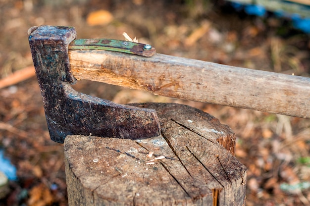 chopping wood with ax. Ax stuck in a log of wood. Old, worn, scratched, sharp ax standing on a wooden, cracked tree stump on a background of chopped wood.