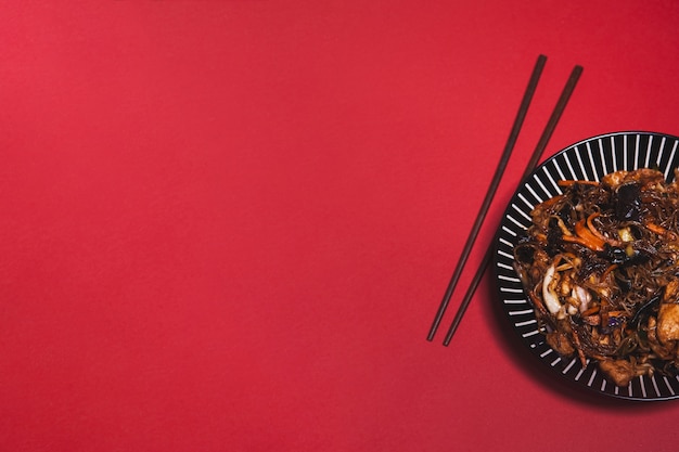 Free photo chopsticks and asian dish on red