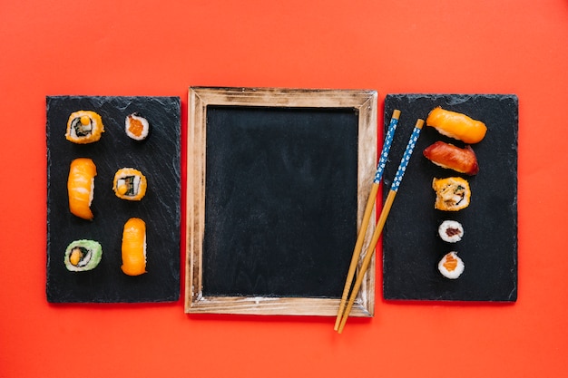 Free photo chopsticks on blackboard between sushi boards