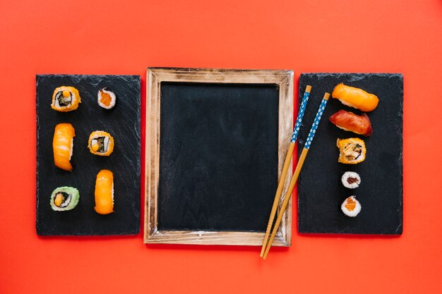 Chopsticks on blackboard between sushi boards