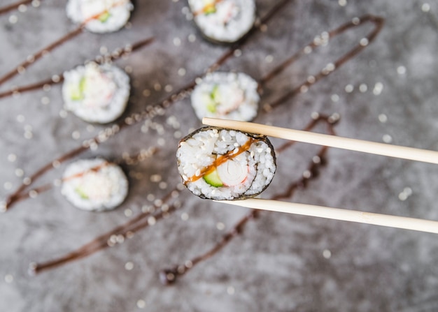 Free Photo chopsticks holding sushi roll with sauce 