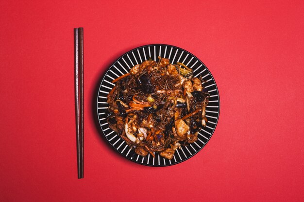 Chopsticks near plate with Chinese food