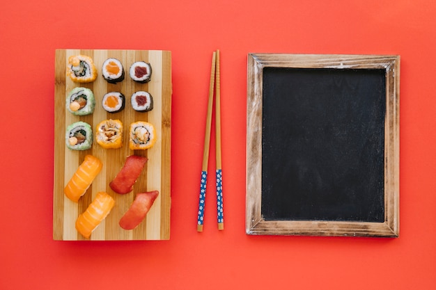 Free Photo chopsticks between rolls and blackboard