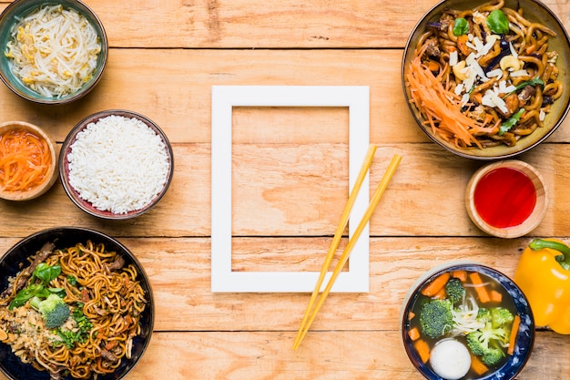 Free photo chopsticks over the white border frame and thai food on wooden desk