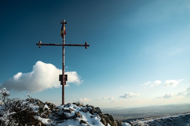 Free photo christian metal cross standing on the rock with a flag