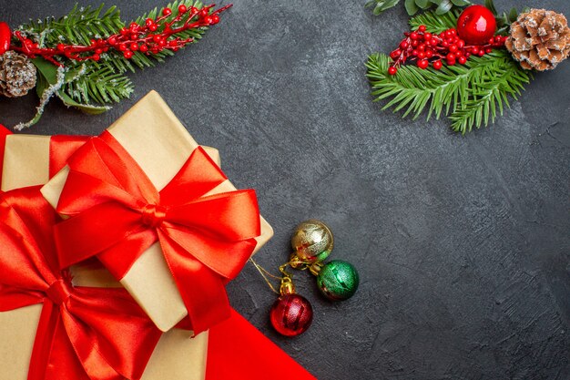 Christmas background with beautiful gifts with bow-shaped ribbon and fir branches decoration accessories on a dark table