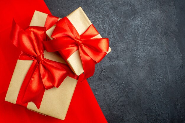 Christmas background with beautiful gifts with bow-shaped ribbon on a red towel on a dark background