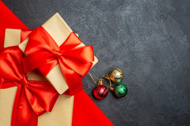 Christmas background with beautiful gifts with bow-shaped ribbon on a red towel and decoration accessories on a dark background