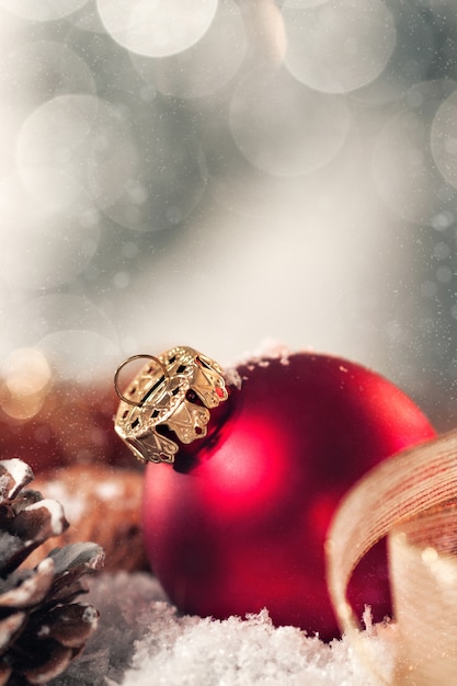 Christmas ball with decoration with candles, fir cones, nuts, snow and ribbon, closeup, toned 