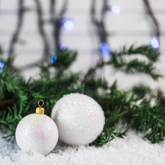 Christmas baubles near fir twig on snow