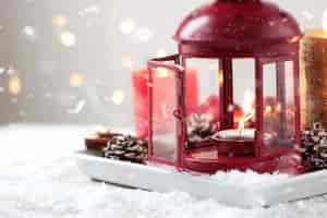 Free photo christmas candles with fir cones, lantern, christmas decoration and snow, winter or holiday concept