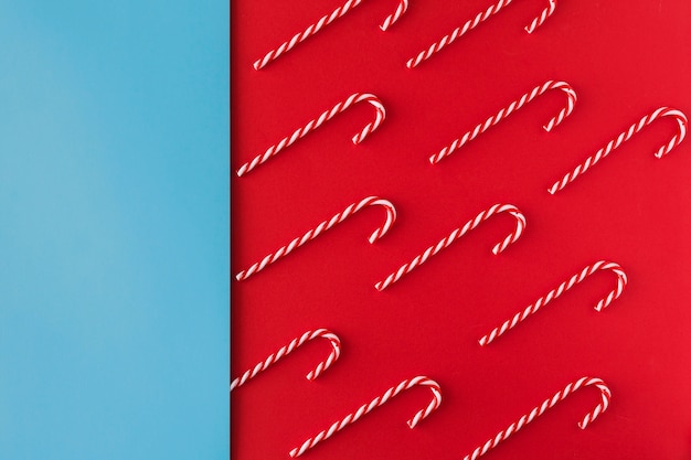 Free photo christmas candy cane on red paper background top view