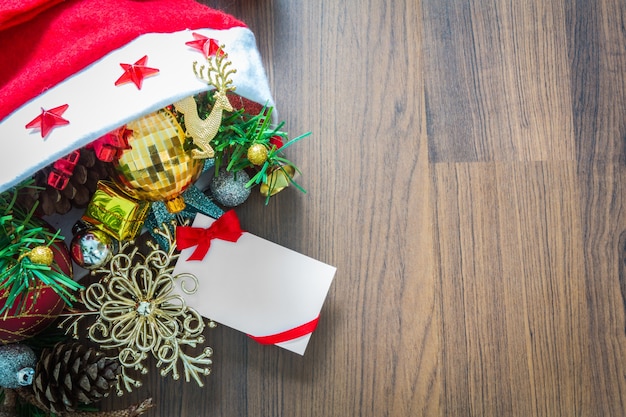 Christmas card and Santa Hat with decorations on wooden backgrou