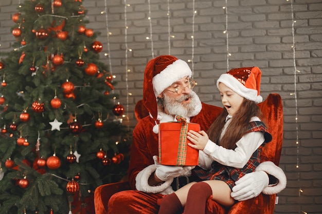 Christmas, child and gifts. Santa Claus brought gifts to kid. Joyful little girl hugging Santa.