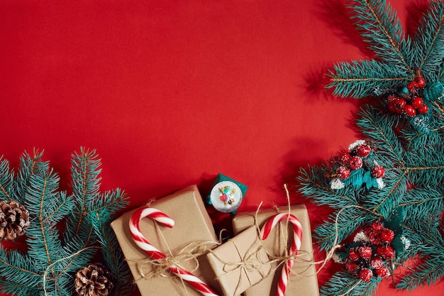 Christmas composition of pine cones, spruce branches and stack of gift boxes on red background