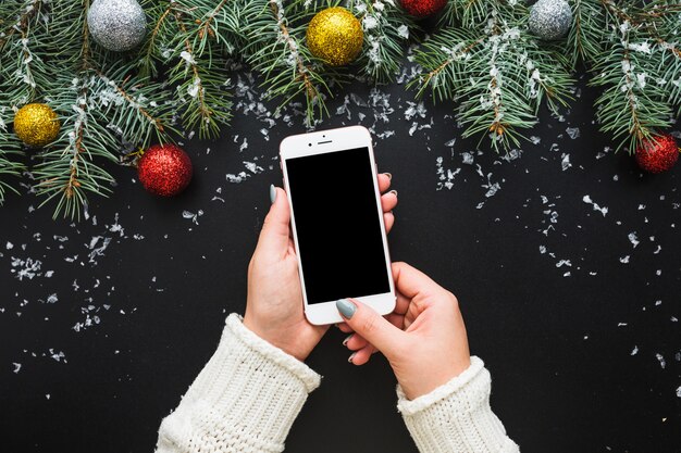 Christmas composition with hands holding smartphone