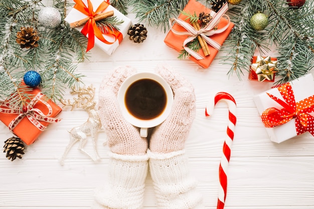 Free photo christmas composition with hands wearing gloves touching coffee cup