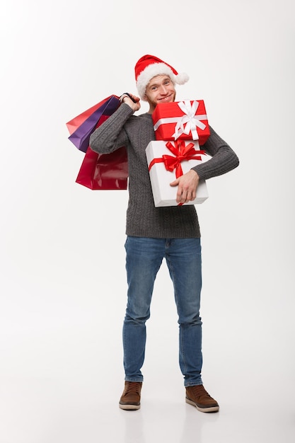 Christmas Concept attractive young caucasian man enjoy shopping holding a lot of presents in Christmas Day