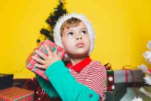 Free photo christmas concepto with with boy shaking present box