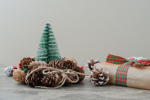 Christmas gift box, pinecones and wreath on marble table.