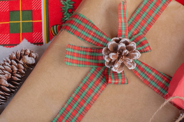 Free photo christmas gift boxes decorated with pine cone on white surface