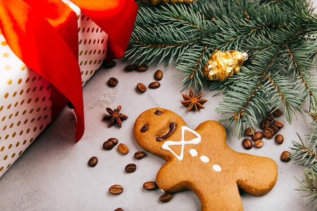 Free photo christmas gingerbread, coffee beans, fir branch and present box on grey floor