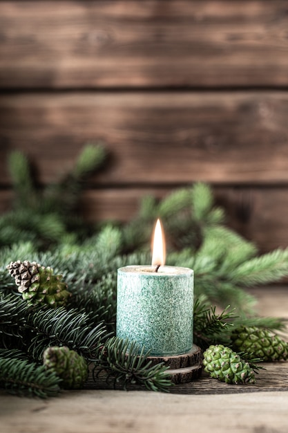 Free Photo christmas green candle with fir branches and cones on wooden table