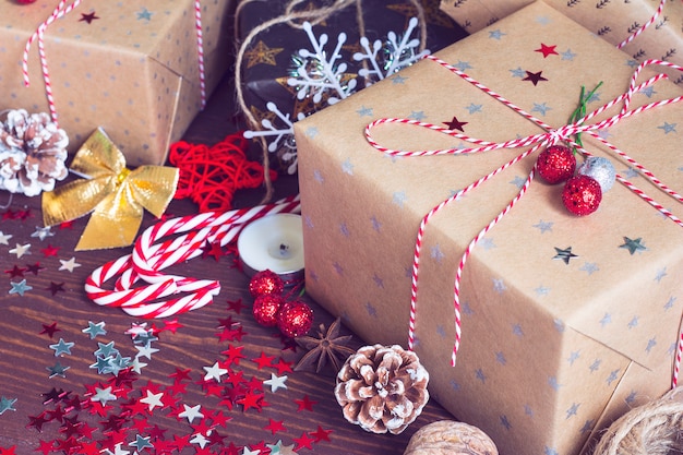 Christmas holiday gift box on decorated festive table with pine cones candy cane nuts and sparkle stars on wooden background