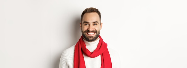 Christmas holidays handsome bearded man in red scarf and sweater smiling white background