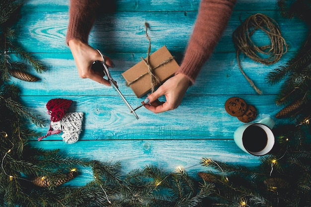 Free photo christmas items on a blue wodden table. woman's hands wrapping christmas gift.