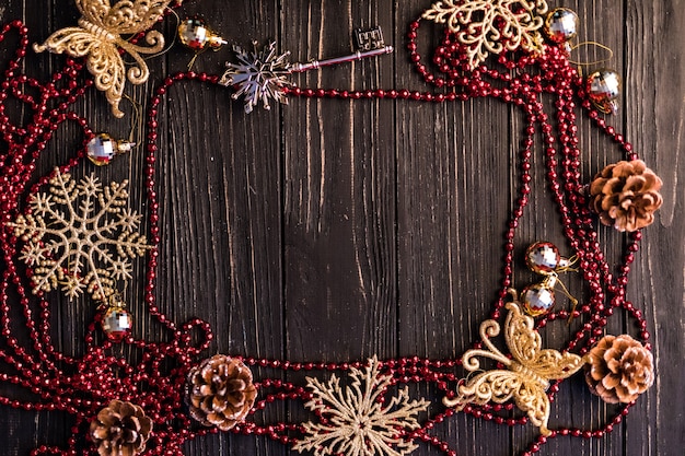 Christmas or new year frame. Christmas branches, fir cones and red necklace on wooden boards