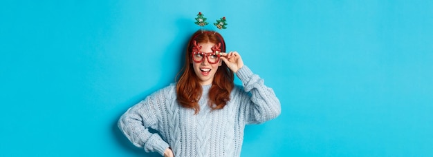 Christmas party and celebration concept cute redhead teen girl celebrating new year wearing xmas tre