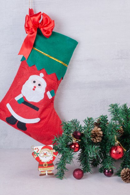 Christmas sock full of festive balls on white surface