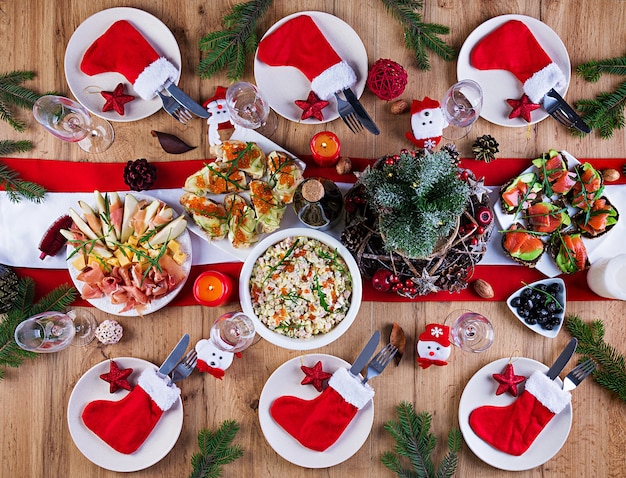 The Christmas table is served with a appetizer, decorated with bright tinsel and candles. Table setting. Christmas dinner. Flat lay. Top view