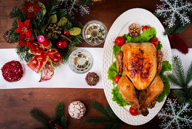 Christmas table served with a turkey, decorated with bright tinsel and candles