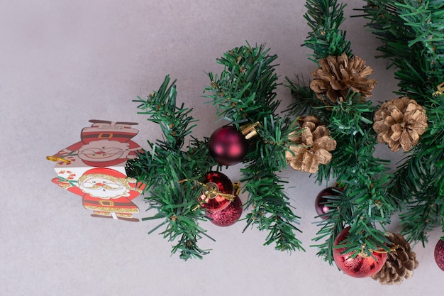 Christmas tree with red balls and pinecones on gray surface