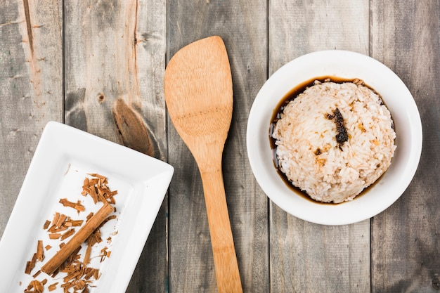 Free Photo cinnamon sticks in white tray with soya sauce rice and spatula on wooden table