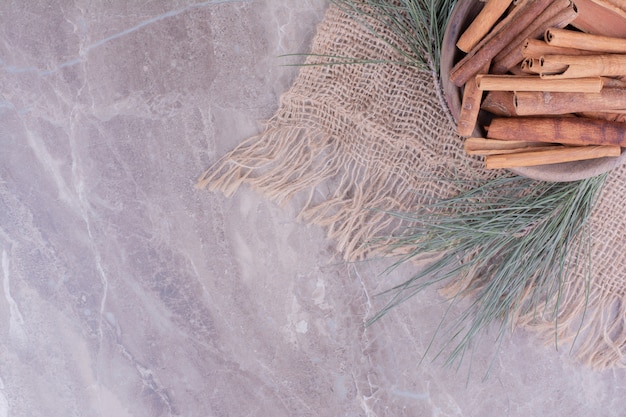 Cinnamon sticks in a wooden cup with oak tree branch around