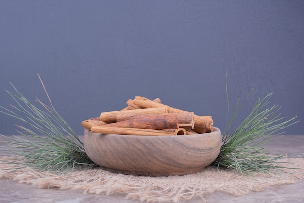 Free Photo cinnamon sticks in a wooden cup with oak tree branch around