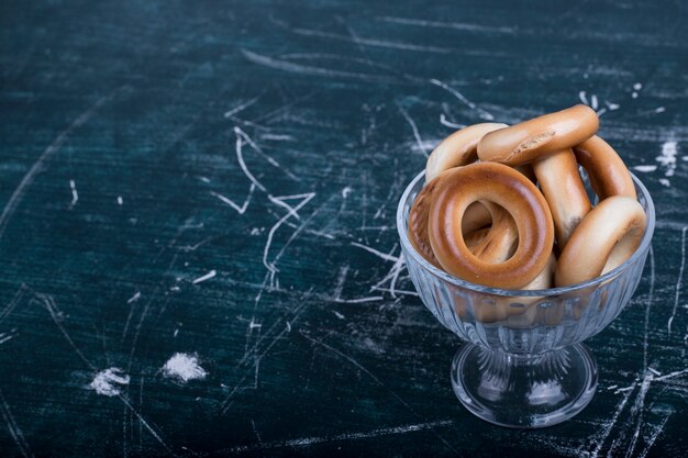 Circle cookies in a glass cup on blue background , angle view. 